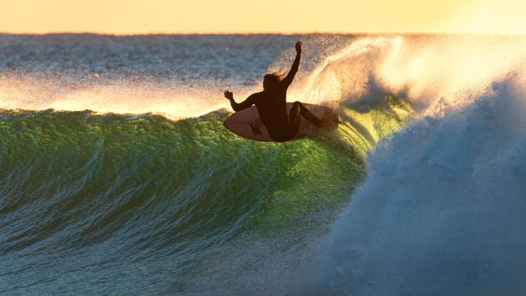 Surfer riding a perfect wave at sunset